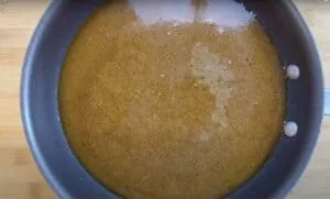 Golden brown gravy simmering in a non-stick frying pan on a wooden surface.